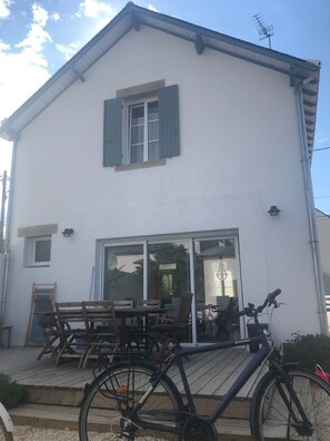 A two-story white building with a balcony, wooden furniture, and a bicycle. - HOUSE VILLA (Batz-sur-Mer)