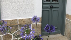 A white textured wall with a green door featuring a decorative window. - HOUSE VILLA (Batz-sur-Mer)