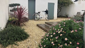A white building with a grey door, a bicycle parked in front, and a gravel pathway leading to the entrance. - HOUSE VILLA (Batz-sur-Mer)