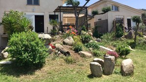 A residential property with a garden featuring rocks, shrubs, and flowering plants. - 50 m2 basement apartment (ceiling height 1.80 m) (Figari)