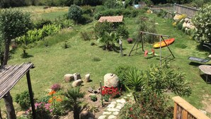 A lush garden with a swing set, a small shed, and a variety of plants and flowers. - 50 m2 basement apartment (ceiling height 1.80 m) (Figari)