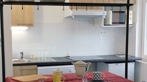 A compact kitchen with a red table, a red chair, and a microwave above the counter. - Apartment Font Romeu (Font-Romeu-Odeillo-Via)