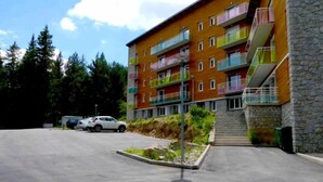 A multi-story building with balconies, a parking area, and a stone wall. - Apartment Font Romeu (Font-Romeu-Odeillo-Via)