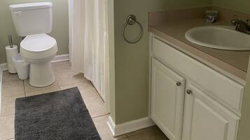 A bathroom with a toilet, sink, and shower curtain.