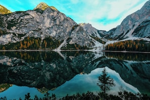 Un lago de montaña con reflejos de las cumbres y árboles circundantes.