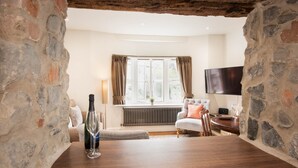 Une pièce chaleureuse avec des murs en pierre, un plancher en bois, un canapé confortable, une table à manger et un téléviseur.