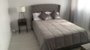 Un dormitorio con cama, mesita de noche y dos cuadros en la pared.