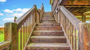 Eine Holztreppe führt zu einem Gebäude mit Blick auf den Ozean.