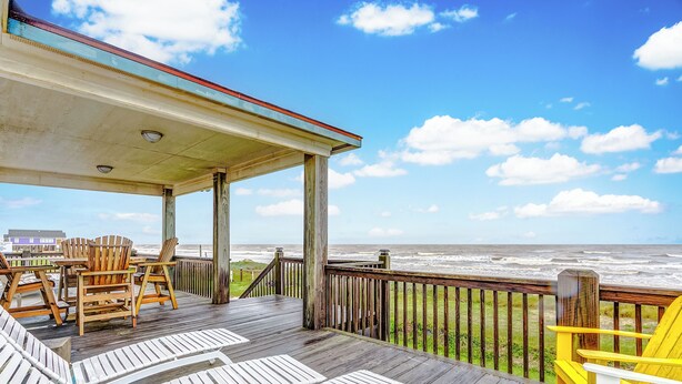 Eine Holzterrasse mit Liegestühlen und Blick auf das Meer.