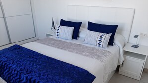 A neatly made bed with a blue blanket, white bedding, and patterned pillows. - MARINE SENATOR (Costa Teguise)