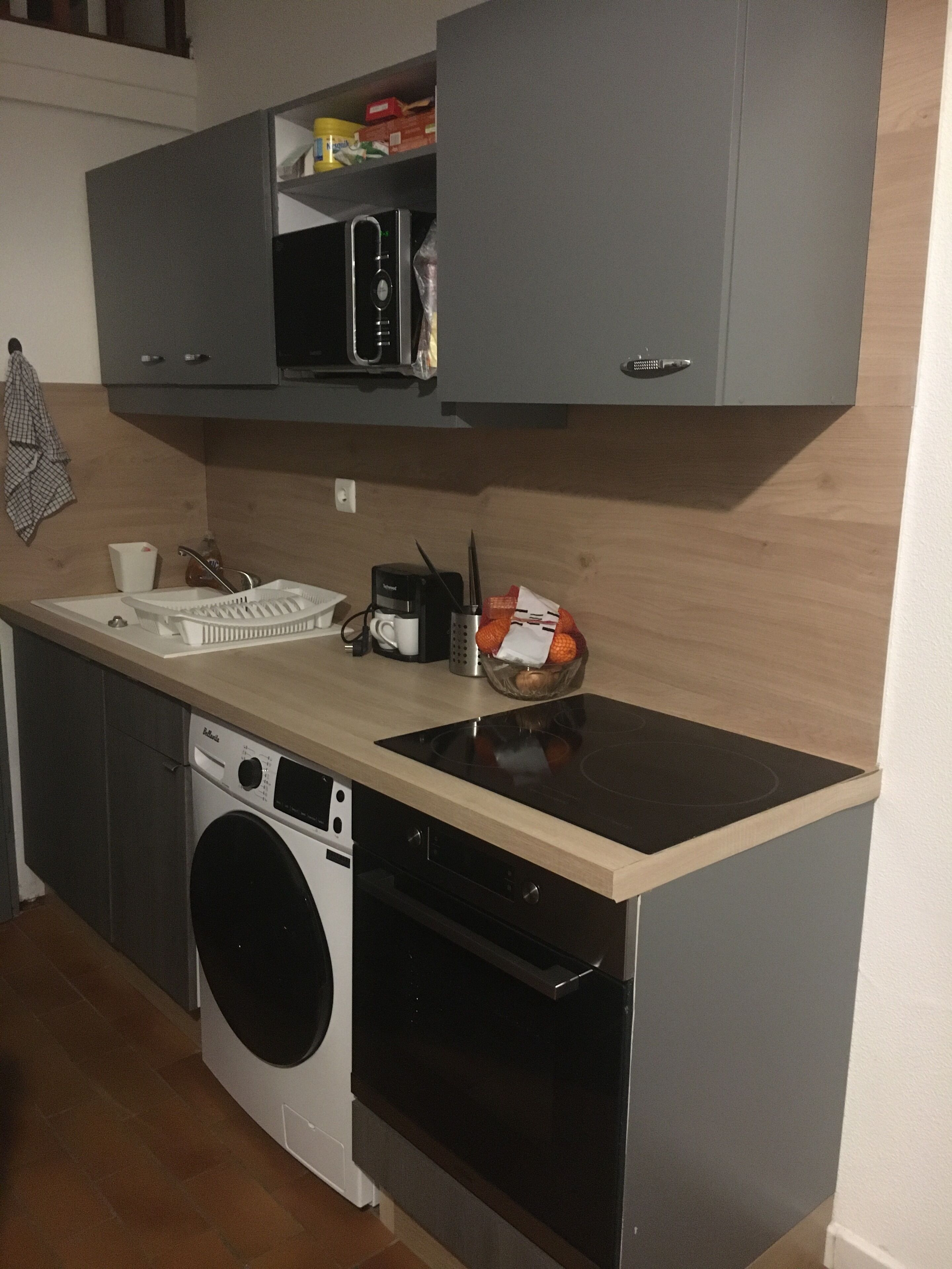 A compact kitchen with a washing machine, a microwave, and a sink.