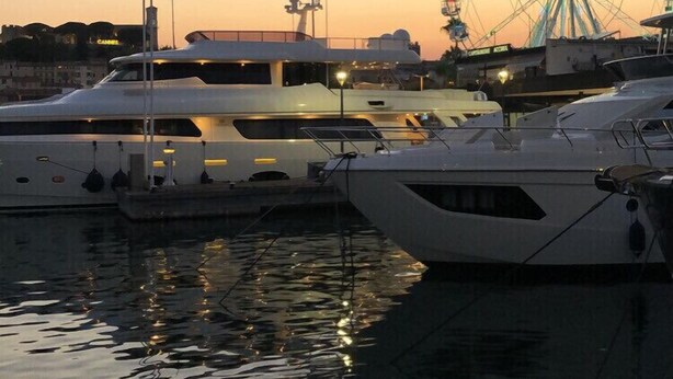 Een jachthaven met aangemeerde jachten, een reuzenrad op de achtergrond en de tekst 'CANNES' die de locatie aangeeft.