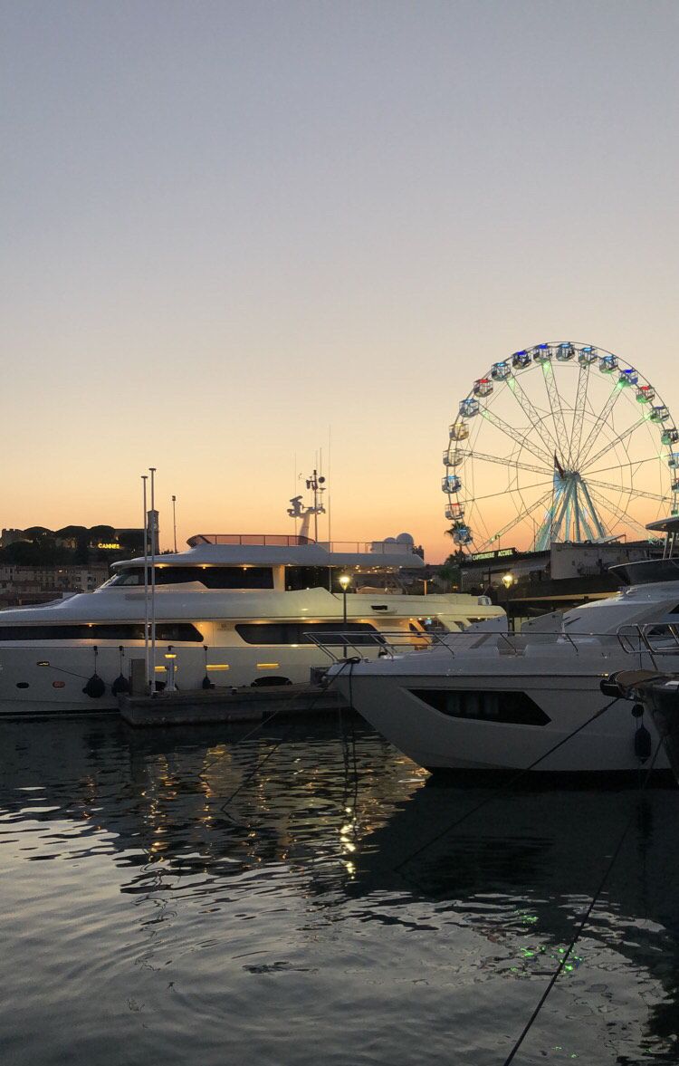 A marina with yachts docked, a Ferris wheel in the background, and the text "CANNES" indicating the location.