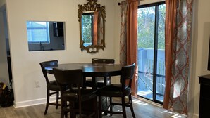 A dining area with a table and chairs, a ceiling fan, a large mirror, and a view through a sliding glass door. - 2144 New Bayfront Condo overlooking Mobile Bay (Daphne)