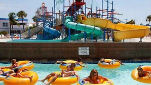 Un parc aquàtic amb diverses tobogans i una zona de piscina on hi ha gent flotant en fons de cartó.