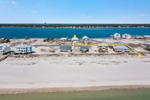 A coastal property with multiple buildings, a sandy beach, and a large body of water.