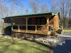 A log cabin with a porch, windows, and a staircase leading to the entrance.