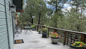 Une terrasse en bois, dotée de meubles d’extérieur, de plantes en pot et d’une rambarde.