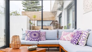A modern living room with a light grey sofa, patterned cushions, a wooden coffee table, and a bowl of fruit. - Villa-4bedroom-3bathroom-pool-petfriendly (Nazaré)