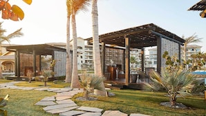 A courtyard with stone pathways, palm trees, and wooden pergolas.