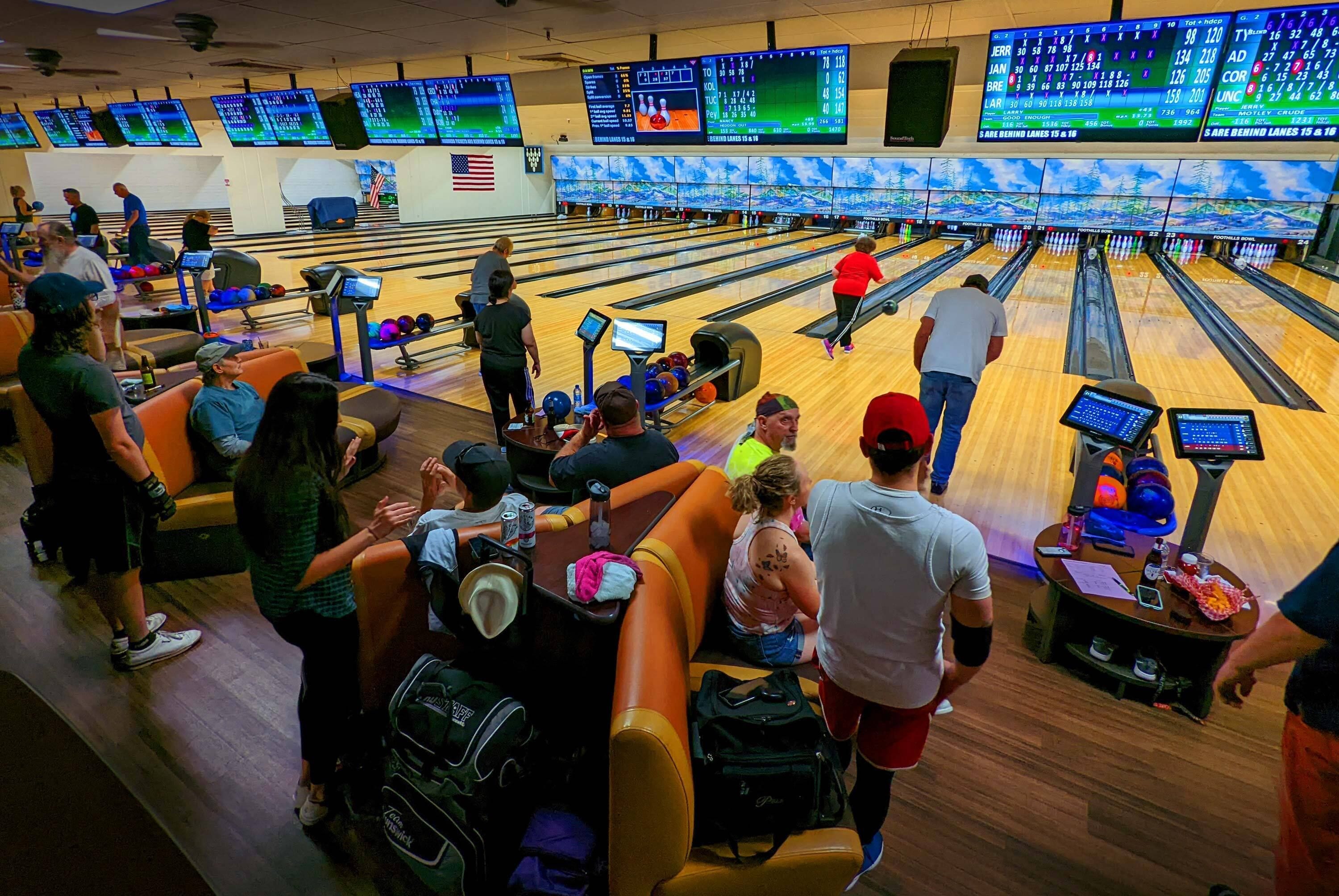 A bowling alley with multiple lanes, a seating area, and a scoreboard displaying scores.