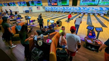 A bowling alley with multiple lanes, a seating area, and a scoreboard displaying scores.