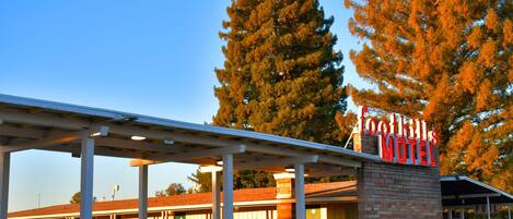 A motel with a prominent sign, covered parking area, and a building with a brick facade.