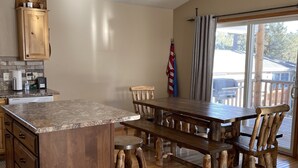 Una cocina con armarios de madera, encimera de granito y comedor con mesa y sillas de madera.