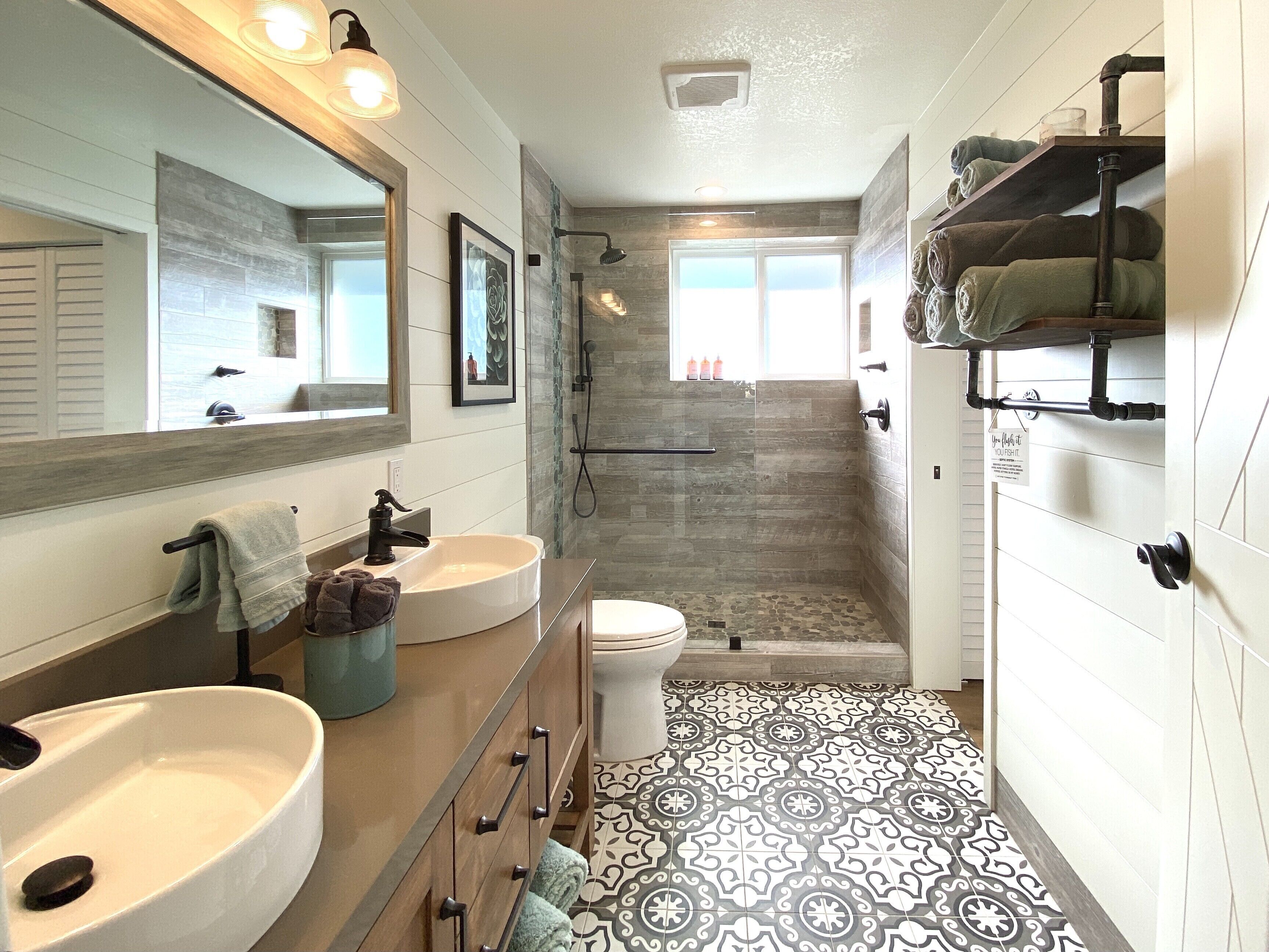 Een moderne badkamer met twee wastafels, een toilet en een douche.