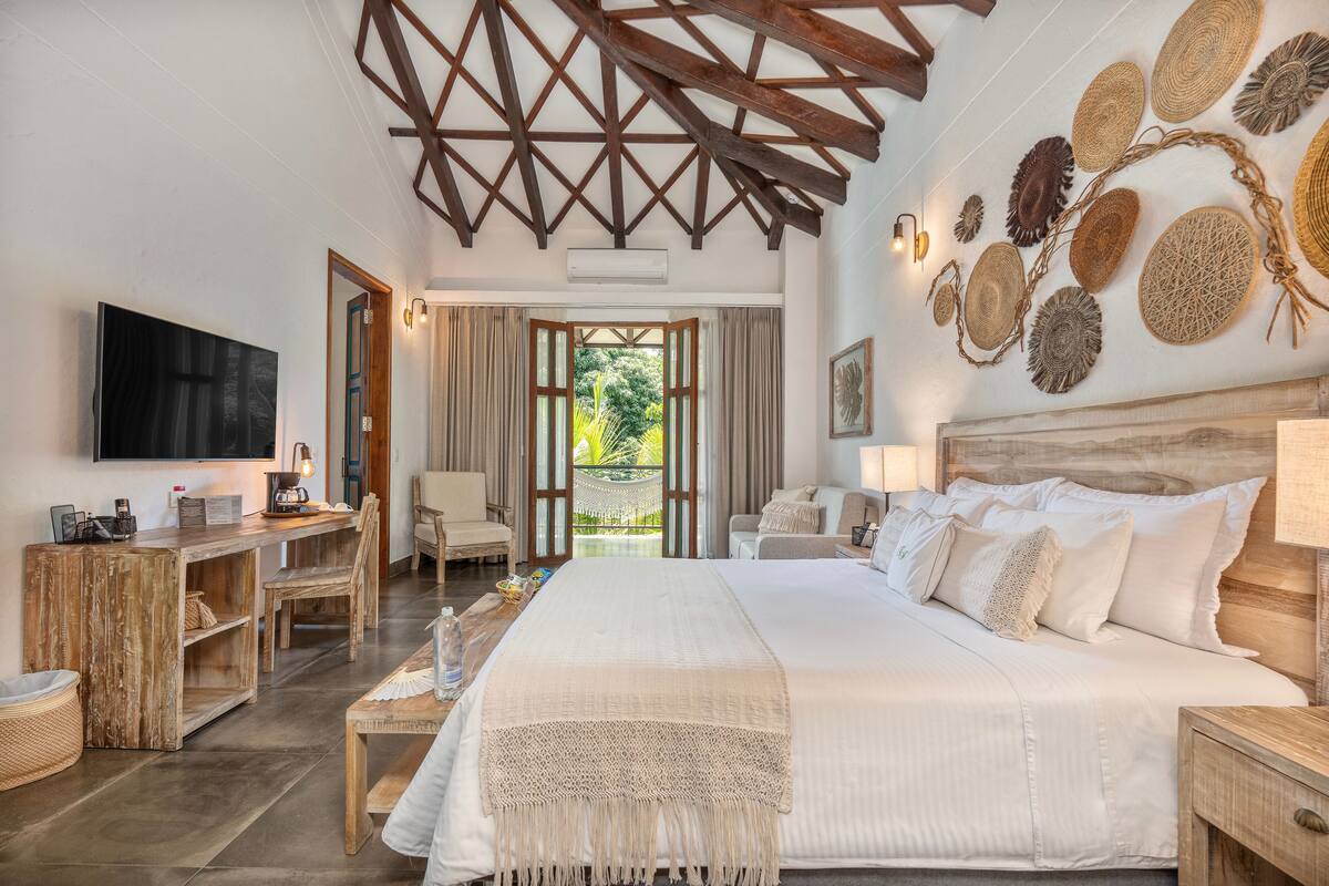 Une chambre spacieuse avec un grand lit, un bureau en bois et une télévision.