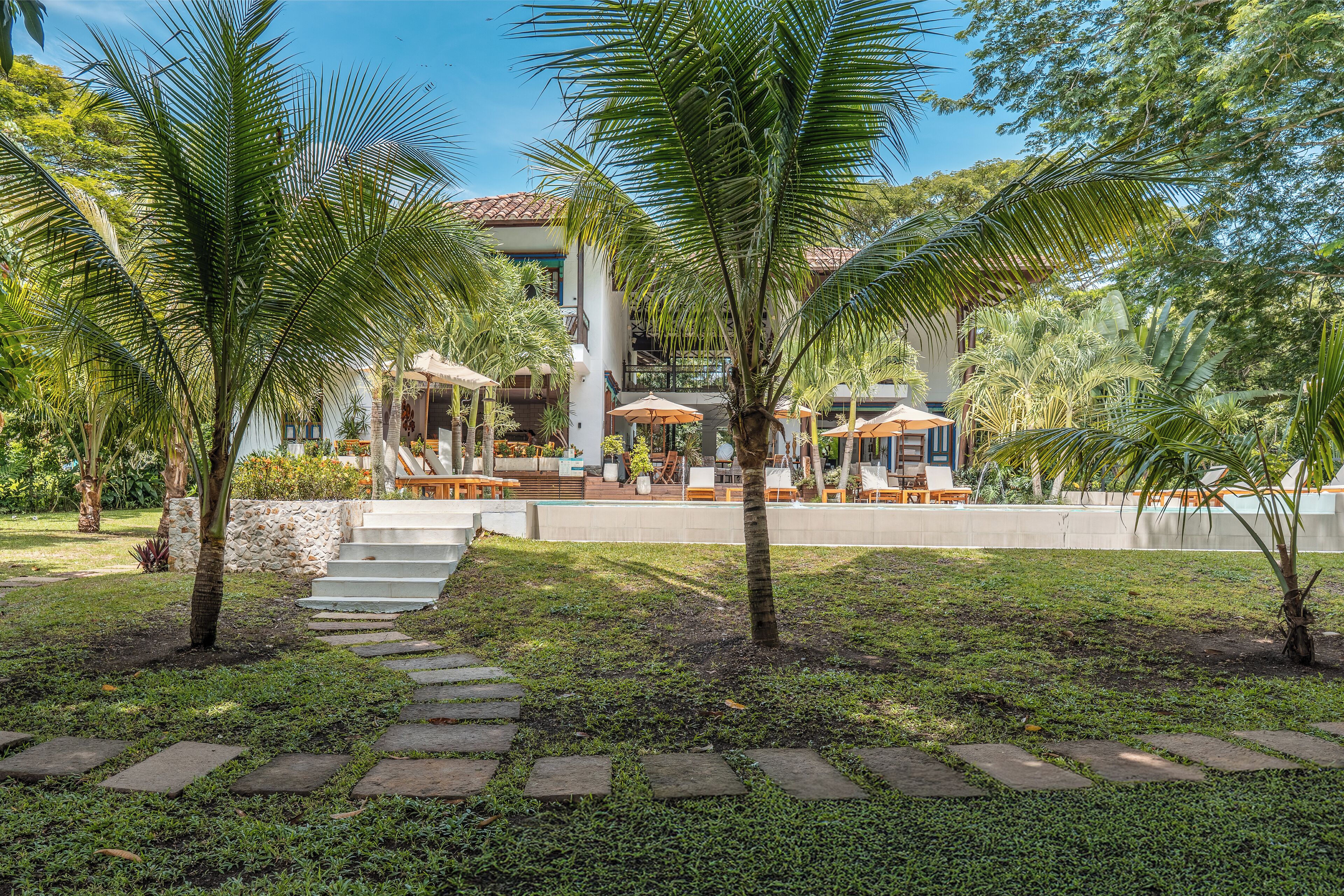 A resort with a pool area, palm trees, and outdoor seating.