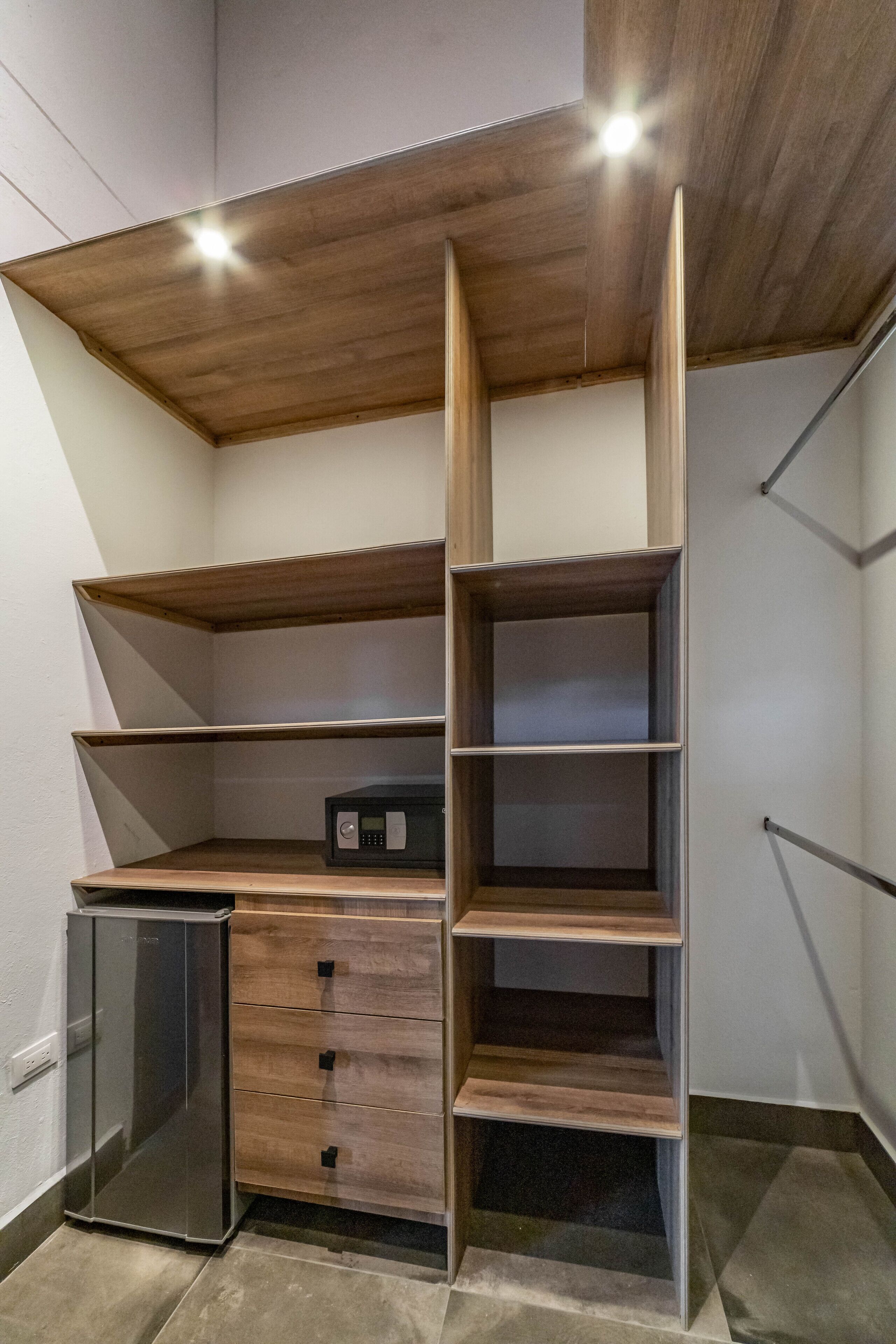 Eine kompakte Küche mit integrierten Geräten, Holzregalen und einem kleinen Kühlschrank.
