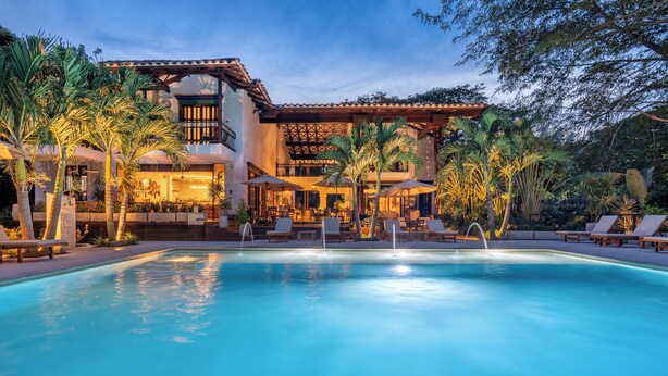 A poolside area with lounge chairs, a bar, and a building with a tiled roof and multiple levels. - Casa Jacaranda Hotel Boutique - Cauca Viejo - Mayores de 14 años (Jericó)