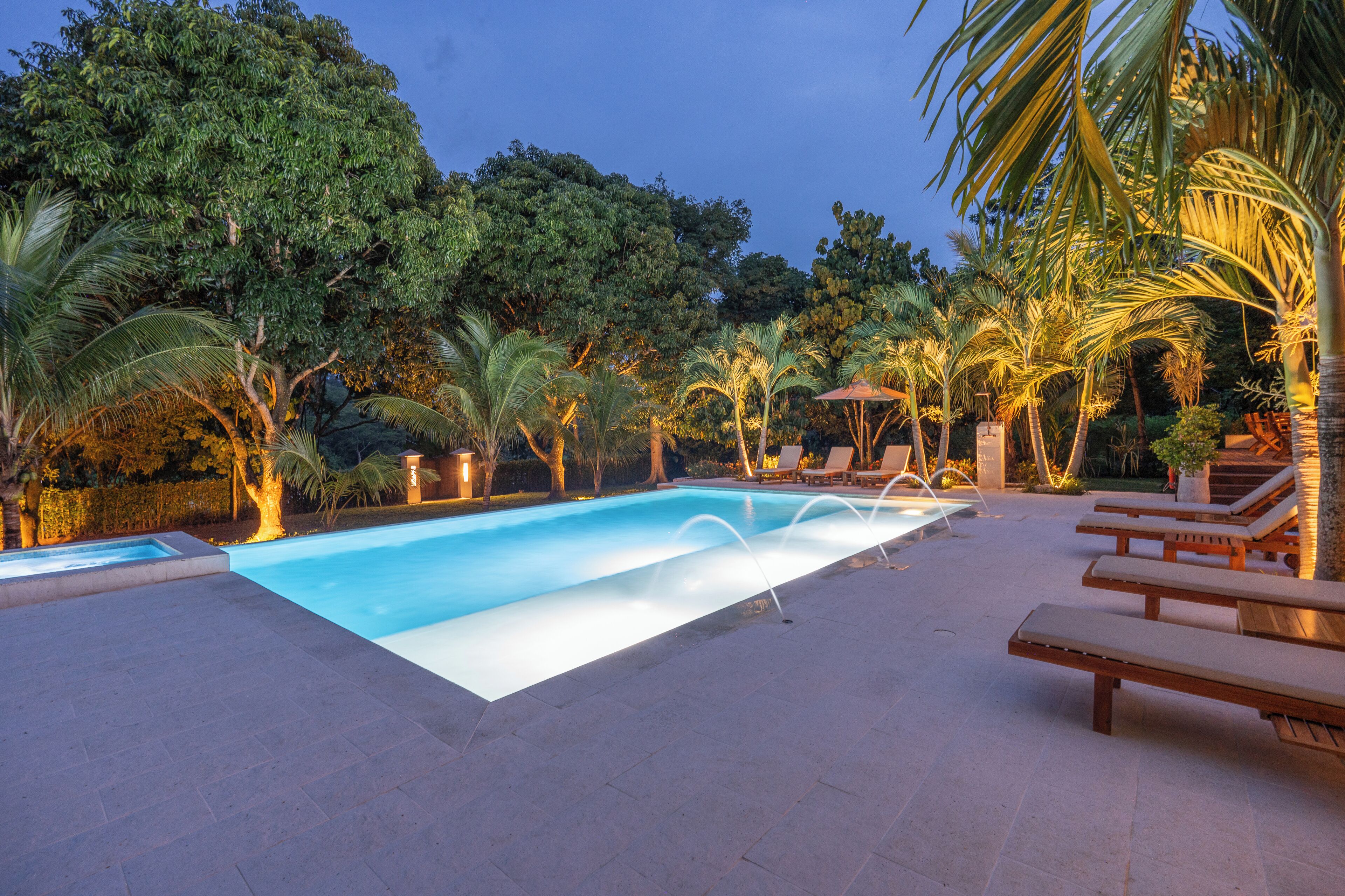 Una piscina con sillas de descanso y palmeras.