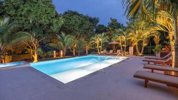 Una piscina con sillas de descanso y palmeras.