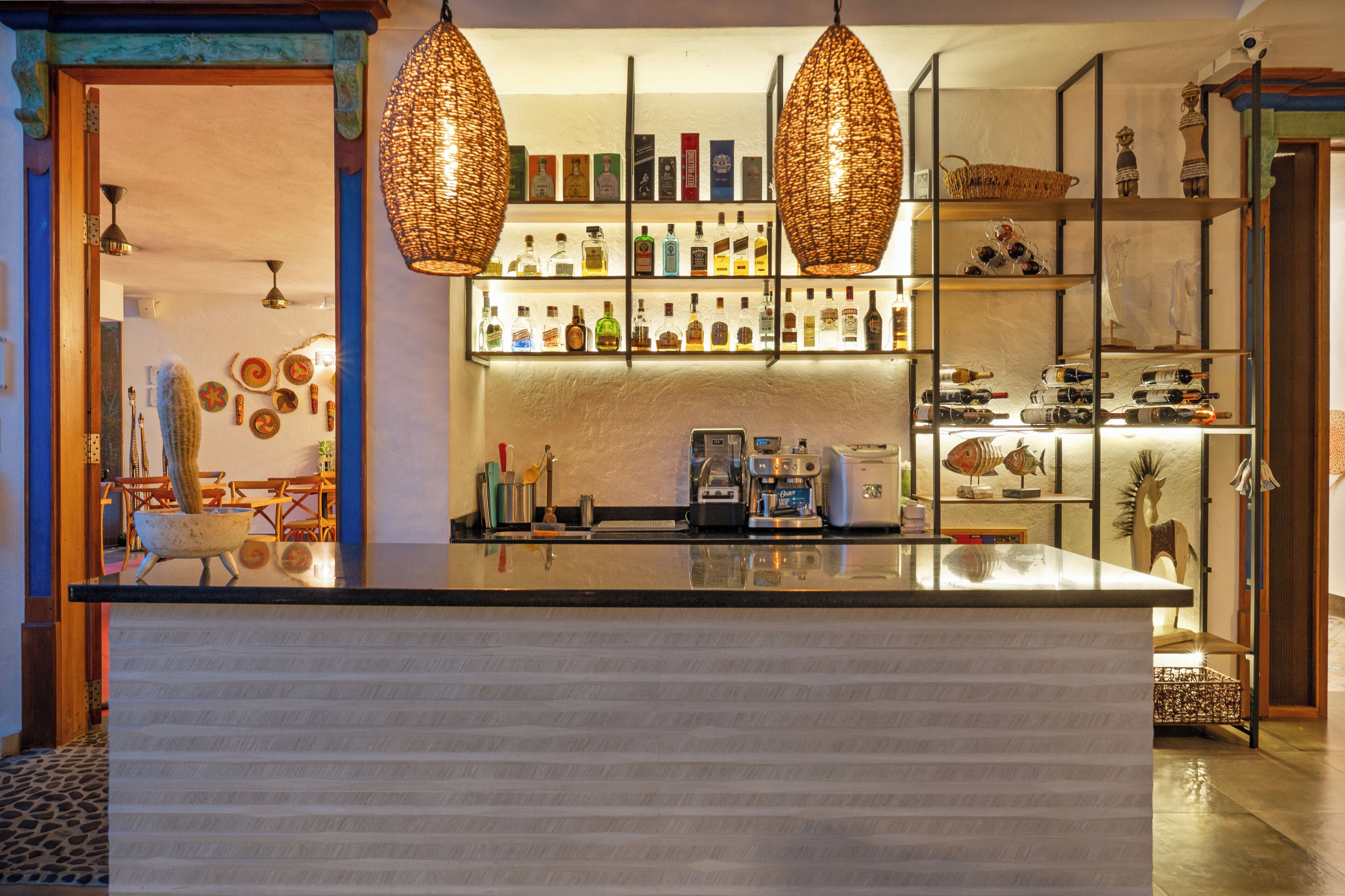 A bar area with a counter, shelves with bottles, and decorative items.