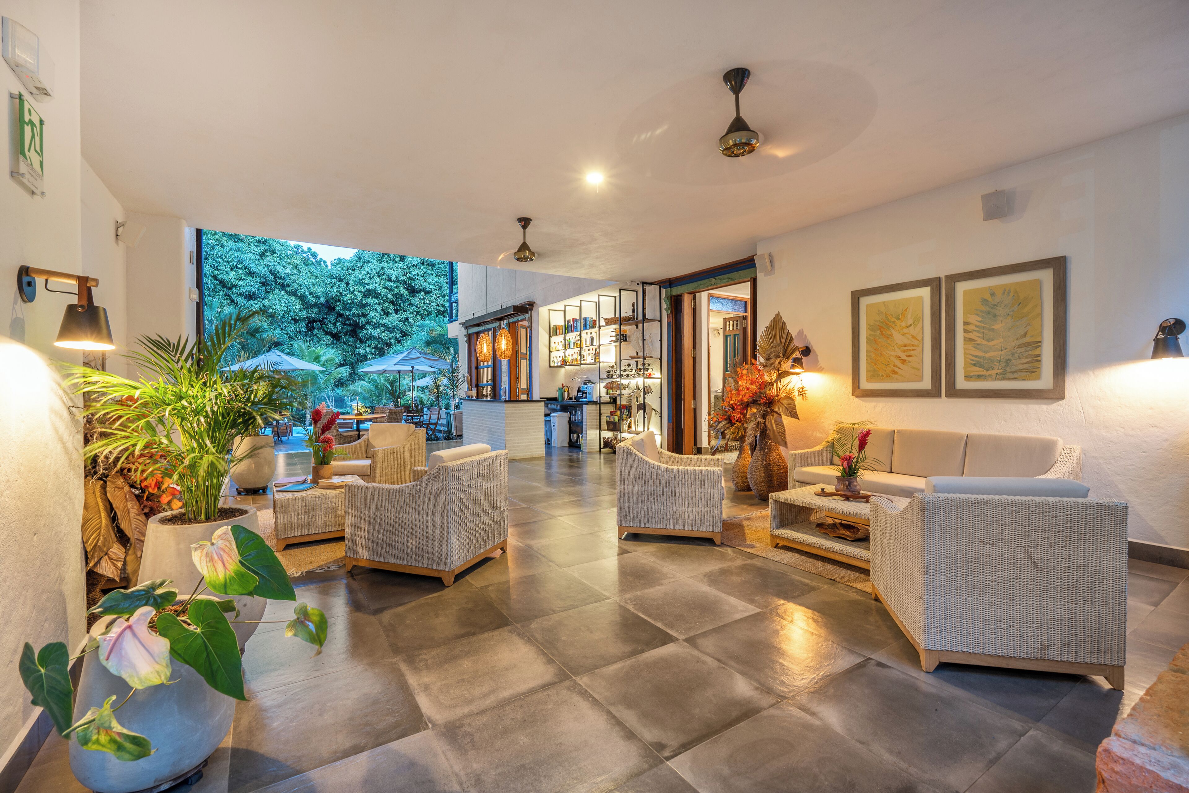 A spacious indoor area with wicker furniture, a reception desk, and a view of the outdoors.