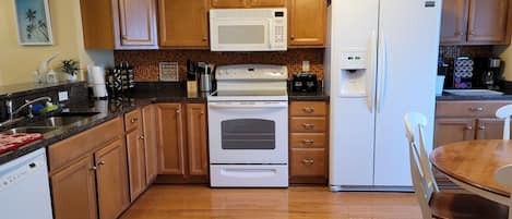 A kitchen with wooden cabinets, a white refrigerator, a microwave, a stove, and a water dispenser.