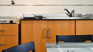 A kitchen with white cabinets, a stainless steel sink, and a black chair. - Hotel Cervantes (Mar del Plata)