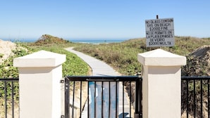 Ein Gartentor am Strand mit einem Schild, das das Mitbringen von Glasbehältern verbietet und eine Strafe von 2000 Dollar bei Verstößen vorsieht.