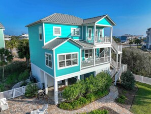 Une maison à deux étages avec un balcon, une terrasse couverte et une cour clôturée.
