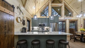 Een moderne keuken met een centraal kookeiland, barstoelen en hanglampen.