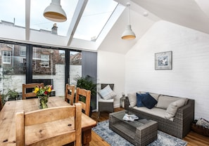A modern living room with a high ceiling, skylight, and a cozy seating area with a sofa and chairs.