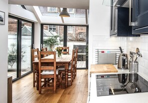 A modern kitchen with a dining area, large windows, and a skylight.