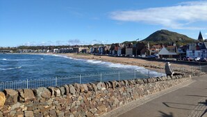 A coastal town with stone walls, a beach, and buildings along the shore. - Central holiday home with pretty, sunny garden, moments from the station, golf course and beach. (North Berwick)