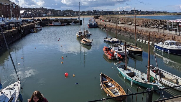 A harbor with various boats docked, a stone wall, and a clear sky. - Central holiday home with pretty, sunny garden, moments from the station, golf course and beach. (North Berwick)