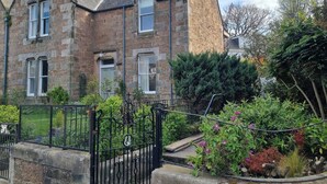 A stone building with multiple windows and a gated entrance. - Central holiday home with pretty, sunny garden, moments from the station, golf course and beach. (North Berwick)