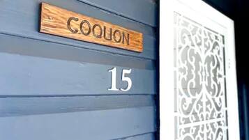 Un rètol de fusta amb el nom "COQUON" i el número "15" a la façana d'un edifici.