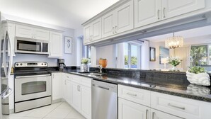 A modern kitchen with white cabinetry, stainless steel appliances, and a black granite countertop. - Endless Summer,Jupiter Walk to Beach & Restaurants! (Jupiter)