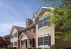 Stunning two-story home with a charming facade, featuring a gable roof, shutters, and a welcoming front porch.